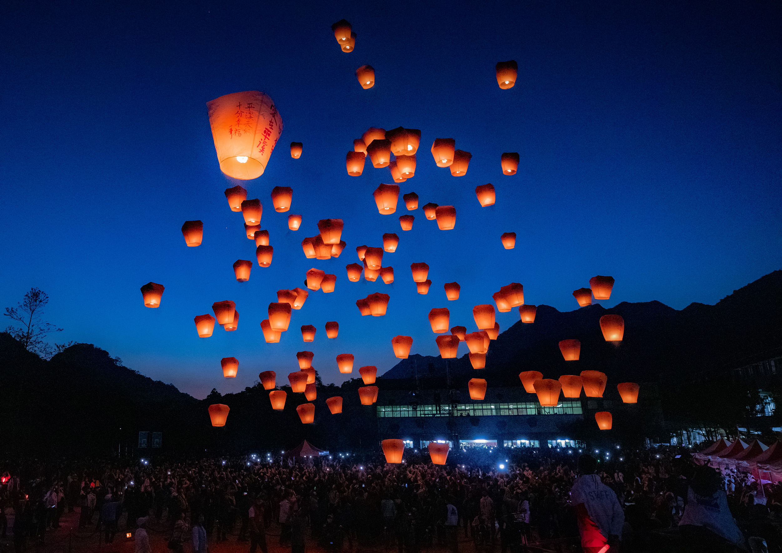 Hundreds of glowing sky lanterns rising into the evening sky at the Pingxi Sky Lantern Festival